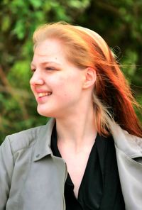 Close-up of smiling young woman against trees