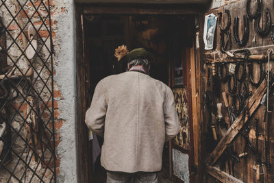 Rear view of man standing at entrance of building