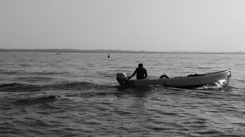 Man on boat in sea against clear sky