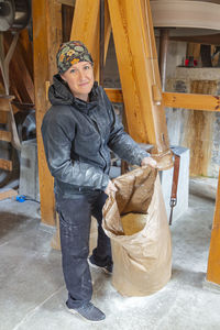 Smiling woman in mill holding sack with flour inside