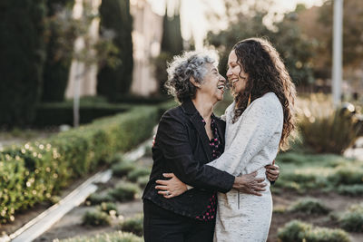 Active senior grandmother and adult daughter hugging outside