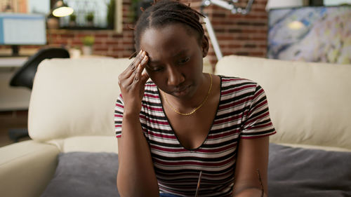 Portrait of young woman sitting on sofa at home