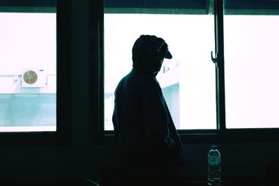 Silhouette man standing by window at home
