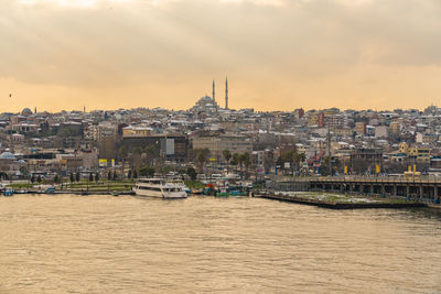 River amidst buildings in city against sky during sunset