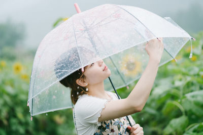 Young woman holding transparent umbrella on rainy day