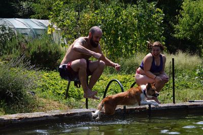 Men and dog on landscape against trees