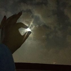 Close-up of hand holding hands against sky at night