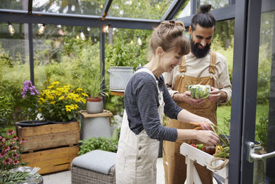 Side view of young woman holding potted plant