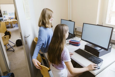 Female students surfing internet on computer at desk in classroom