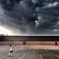 Woman standing on railroad track against cloudy sky