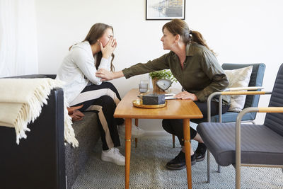 Female therapist consoling teenage patient during session at workshop