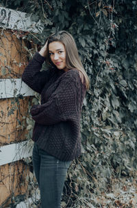 Portrait of young woman standing by wall outdoors