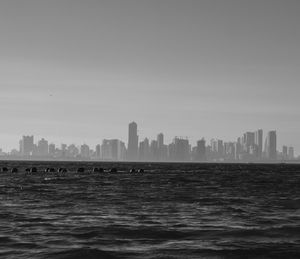 Sea by buildings against clear sky