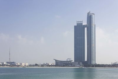 Sea by buildings against sky