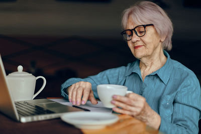 Senior businesswoman with coffee cup working in cafe