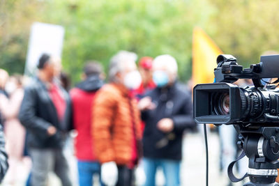 Tv camera lens in the focus, blurred people in the background