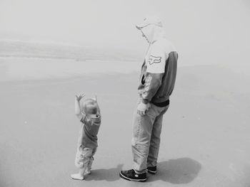 Boy standing on beach against sky