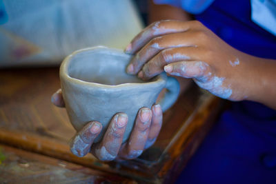 Cropped image of person making cup with clay