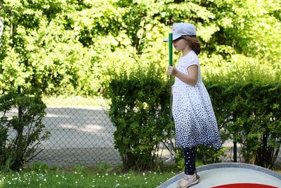 Side view of cute girl holding golf stick in course