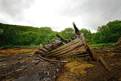 Abandoned wooden structure on field against sky