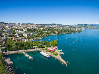 High angle view of townscape by sea against blue sky