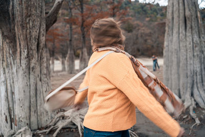 Rear view of woman on tree trunk in forest