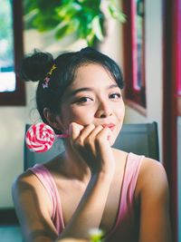 Portrait of smiling young woman holding lollipop