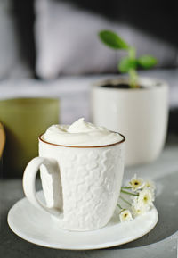 A cup of cappucino coffee on a table next to sofa in living room