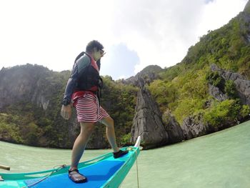 Rear view of woman on boat against mountain and sky