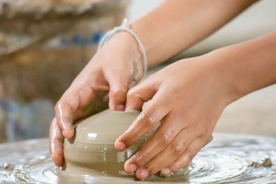 The fingers are shaped clay pot on a rotating tray.