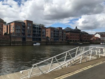 Buildings by river against sky in city