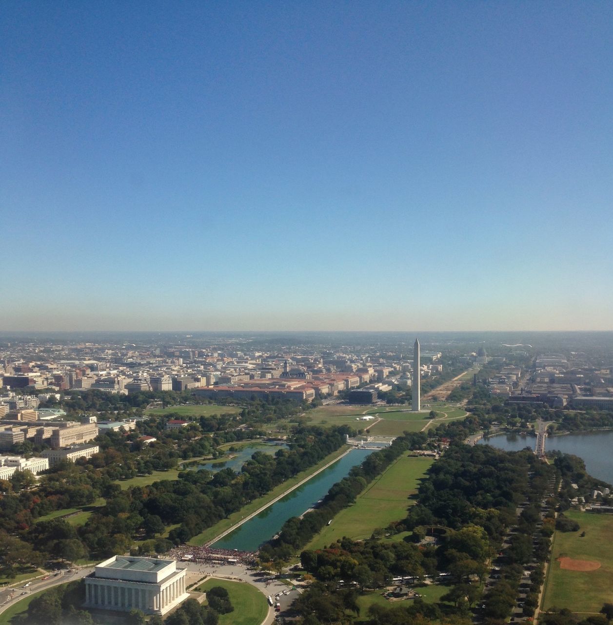 high angle view, cityscape, architecture, built structure, building exterior, city, aerial view, tree, crowded, landscape, residential district, clear sky, copy space, road, horizon over land, residential building, sky, elevated view, blue, transportation