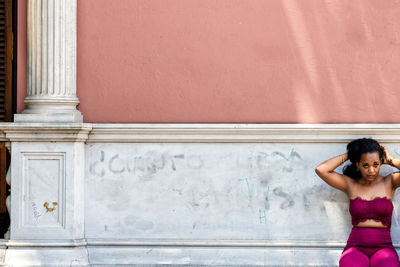 Portrait of woman standing against wall