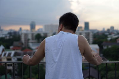 Rear view of man looking at cityscape against sky