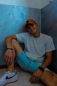 Portrait of a smiling young man sitting against wall