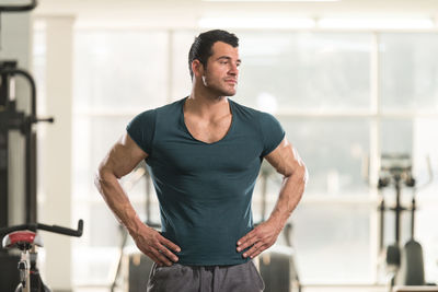 Muscular man looking away while standing in gym