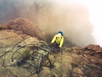 Man working on rock against sky
