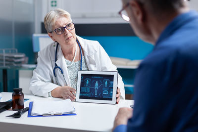 Female doctor showing digital tablet to patient