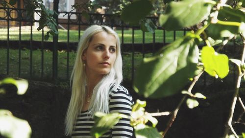 Portrait of young woman standing by tree