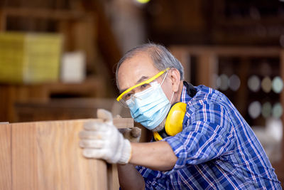 Carpenter, senior man sanding wooden fence in workplace using work tool