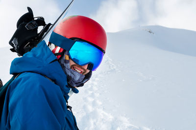 Equipped skier holding skis on his shoulder and looking directly at the camera, portrait. man with