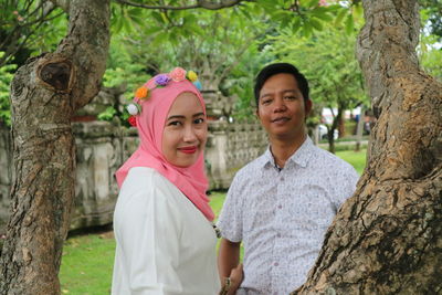 Portrait of a smiling young couple on tree trunk