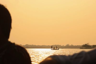 Rear view of silhouette people on beach against sky during sunset