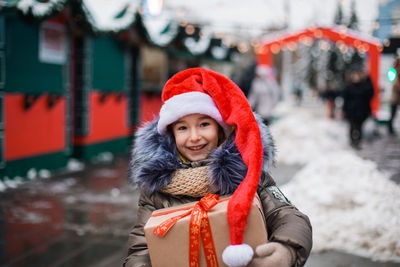 Portrait of girl holding gift box while standing outdoors