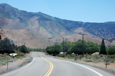 Empty road leading towards mountains against sky