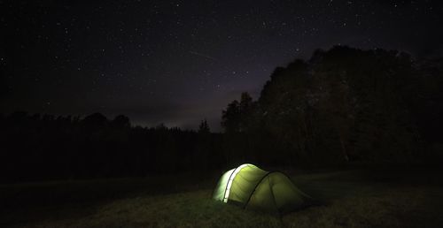 Car on illuminated field against sky at night