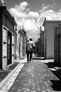 Rear view of man walking on street against sky