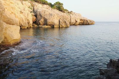 Scenic view of sea and cliff against clear sky