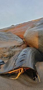 Close-up of tire waste on beach against sky