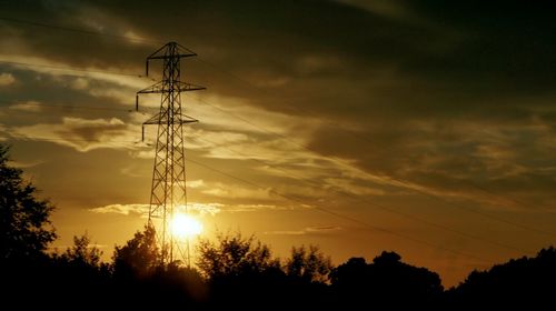 Low angle view of silhouette electricity pylon against sunset sky